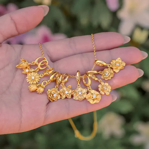 Twelve gold birth flower charms held in an open hand